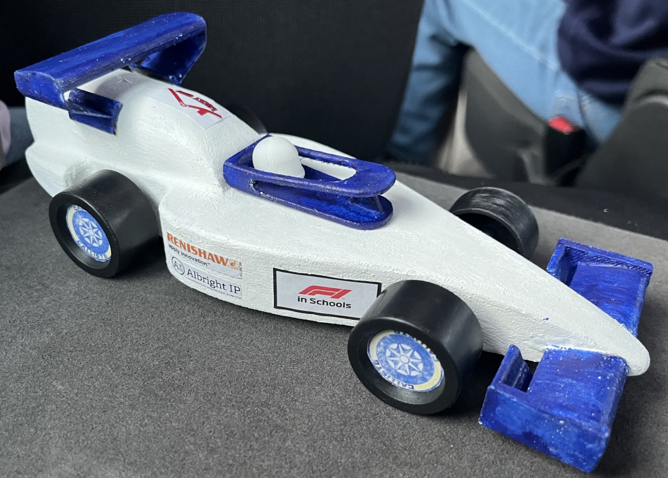 A STEM Racing miniature car with white bodywork and blue wings