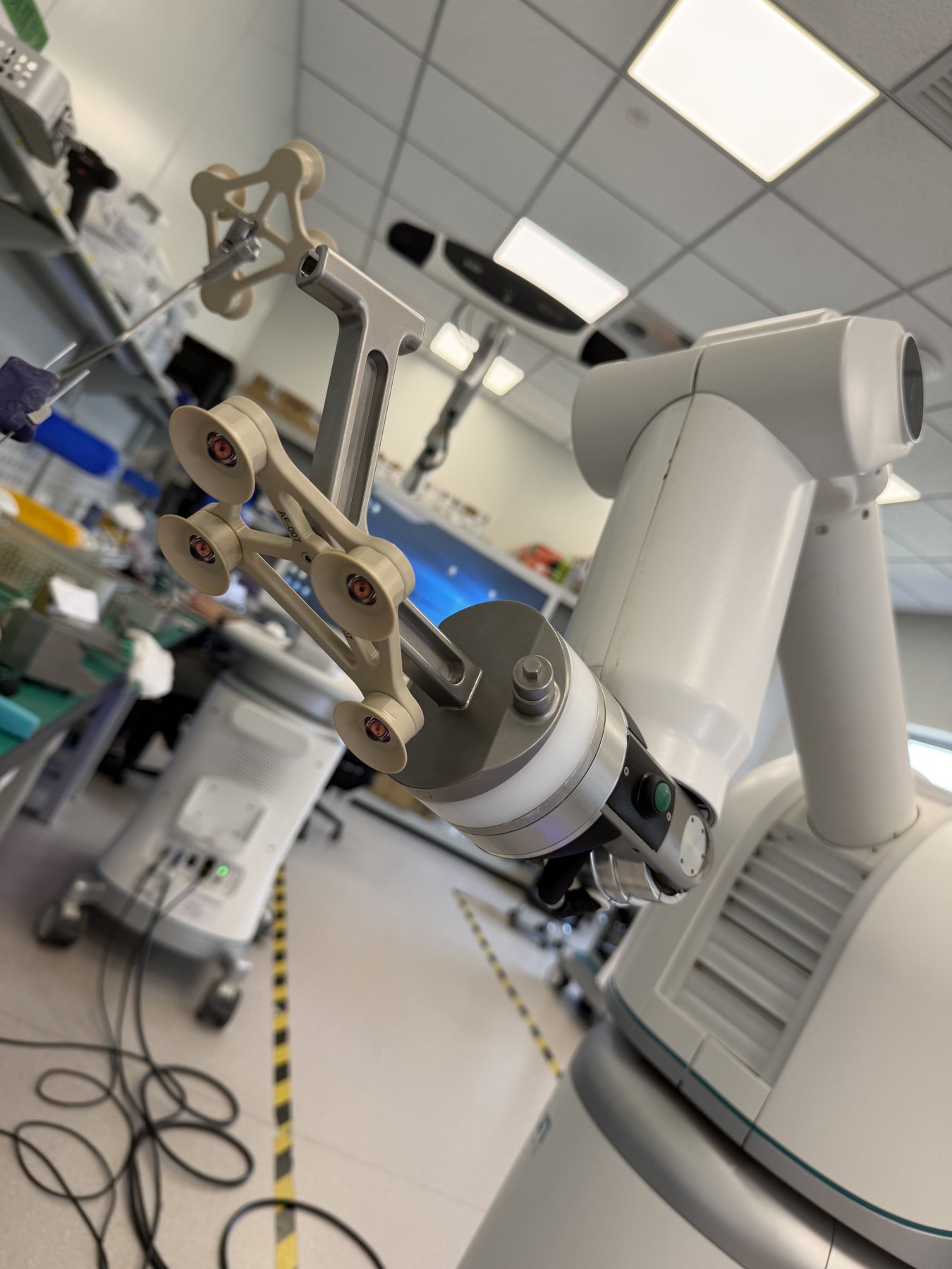 Close-up of a surgical robotic arm with a tool guide and tracking markers
